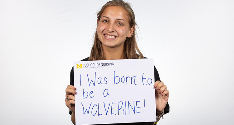 Female nursing student holding a sign I was born to be a Wolverine 