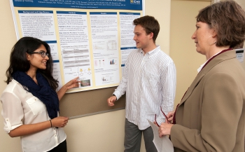 Students Pia Sengupta and J.P. Kelly discuss a poster with Dr. Smith 