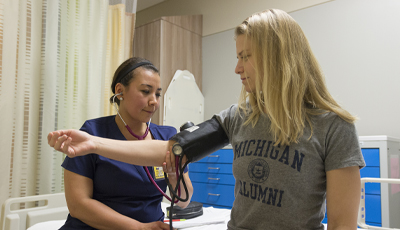 Nurse measuring blood pressure on an alumni