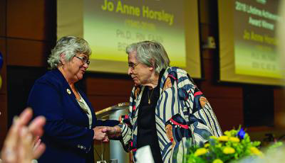 Jo Anne Horsley being congratulated at an event.