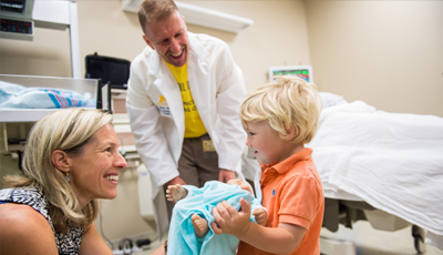 Two faculty with a child holding a child manikin