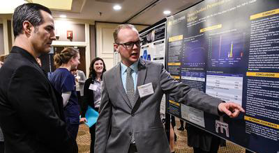 U-M School of Nursing student shows research poster to faculty memeber