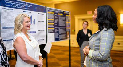 Two U-M School of Nursing students talking next to a research poster