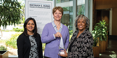 Three people standing with an award