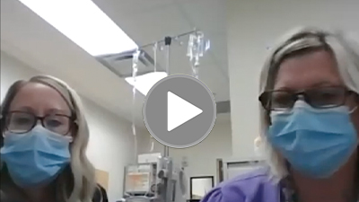 Two nurses with a video play button