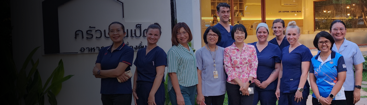 University of Michigan School of Nursing faculty and Thai faculty posing together outside a building in Thailand, highlighting global partnerships to expand the reach and impact of nursing.