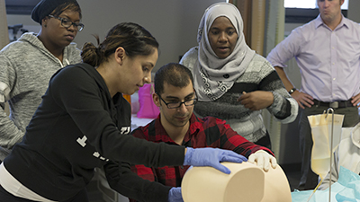 Four students practice suturing on a dummy