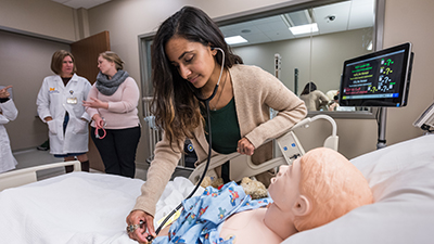 Student examines mannequins in simulation lab