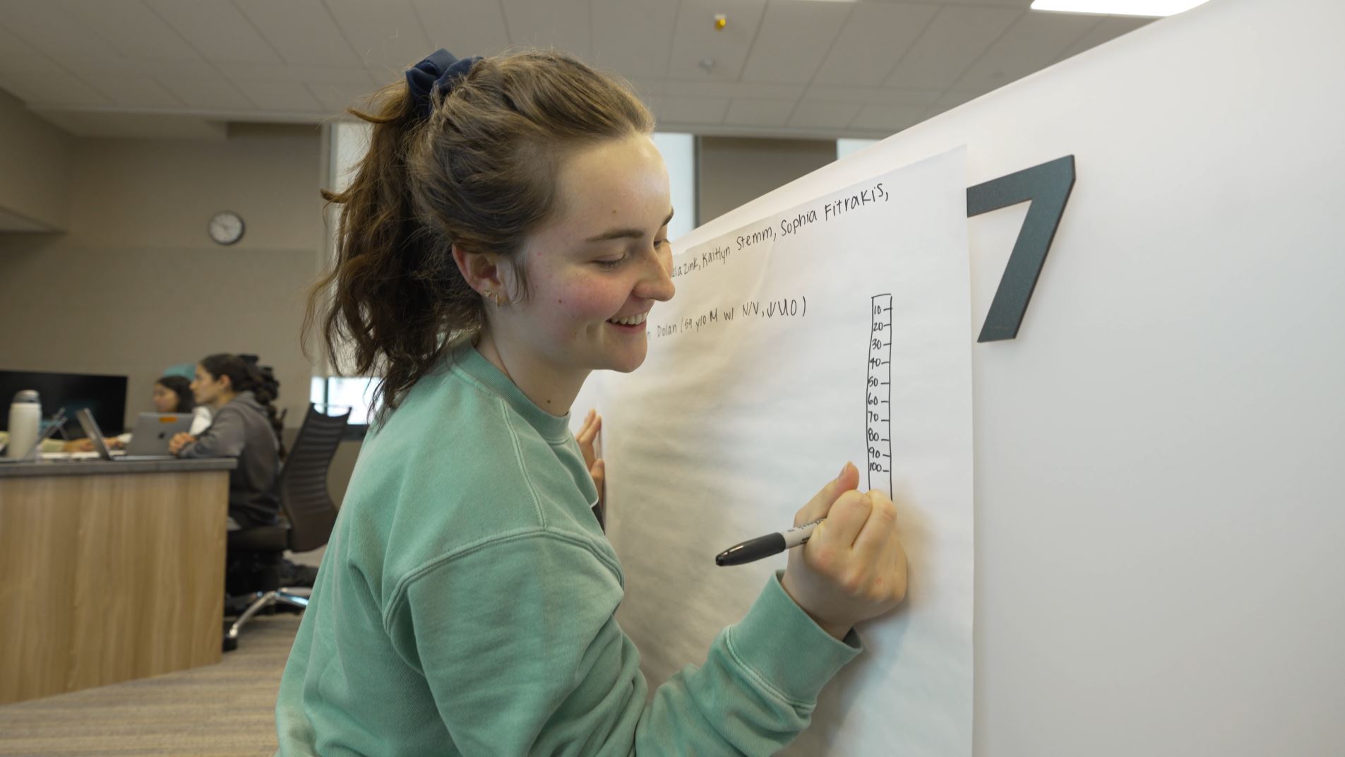 student writing on white board during class