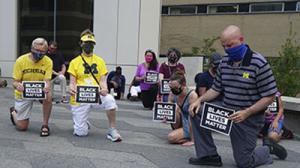 People kneel with black lives matter signs
