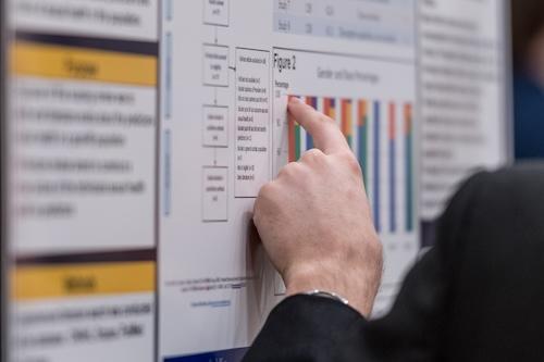 Faculty pointing out key research data on poster